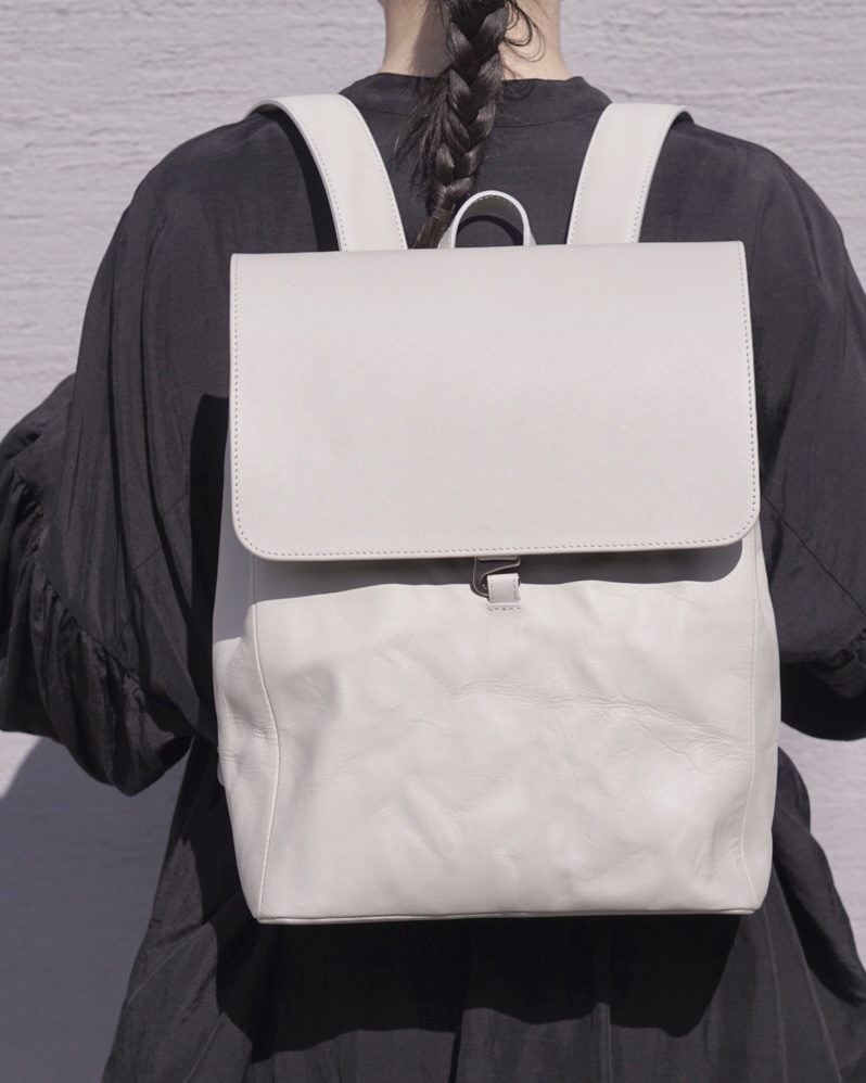 革もの工房tickleの、淡い色の革リュックを背負った後ろ姿