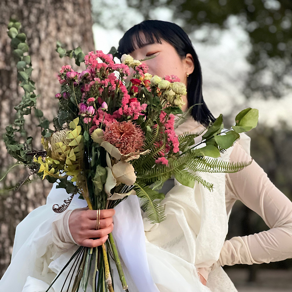 merry_go_roundの、ドライフラワーの花束を両手で持つ様子